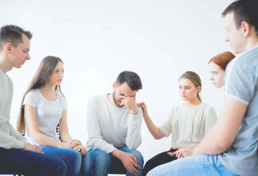 Группа людей утешает мужчину